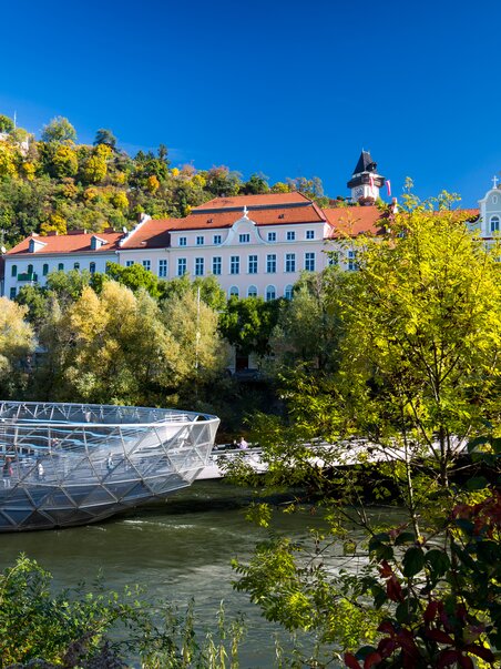 L'isola sul fiume Mur a Graz con uno sfondo pittoresco. | © Graz Tourismus - Harry Schiffer