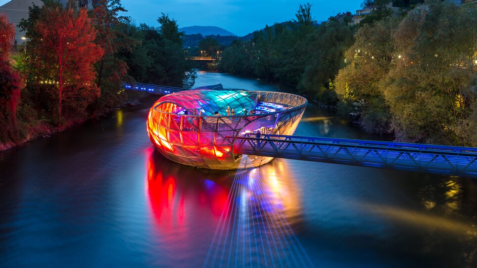 The Island in the Mur in Graz shines colorfully over the Mur. | © Graz Tourismus - Harry Schiffer
