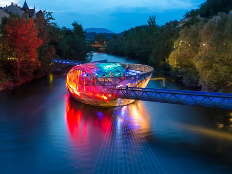 Die Murinsel in Graz leuchtet farbenfroh über der Mur. | © Graz Tourismus - Harry Schiffer