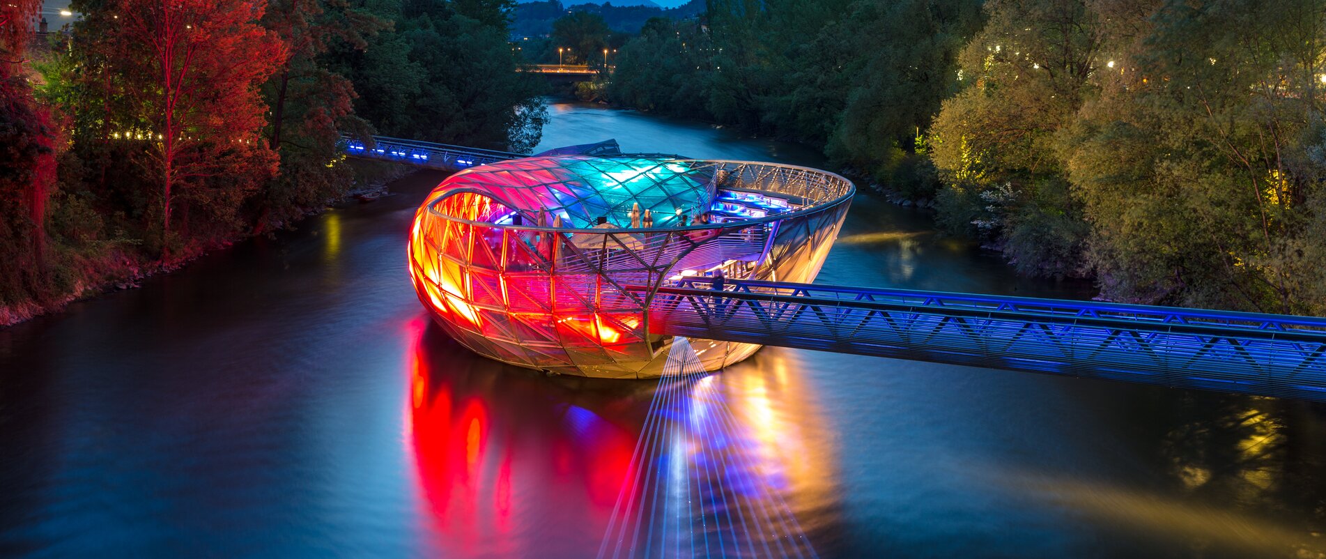 The Island in the Mur in Graz shines colorfully over the Mur. | © Graz Tourismus - Harry Schiffer