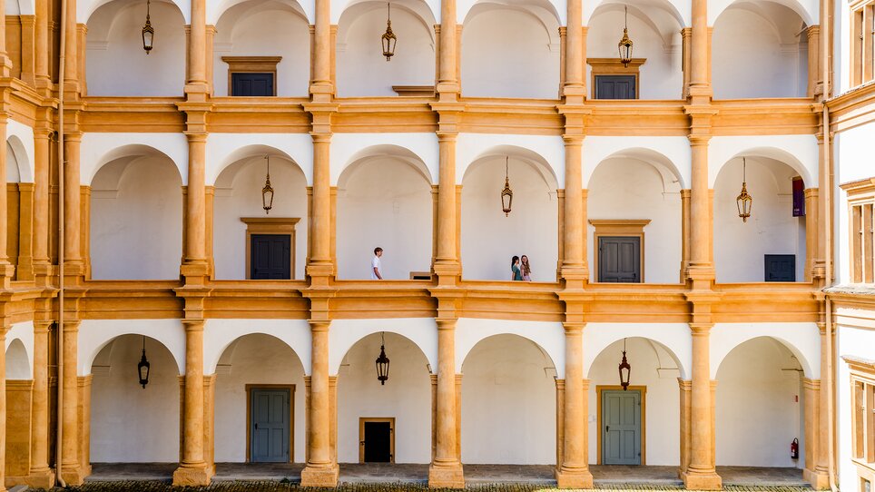 Inner courtyard of Eggenberg Palace with arches and people. | © Graz Tourismus - Mias Photoart