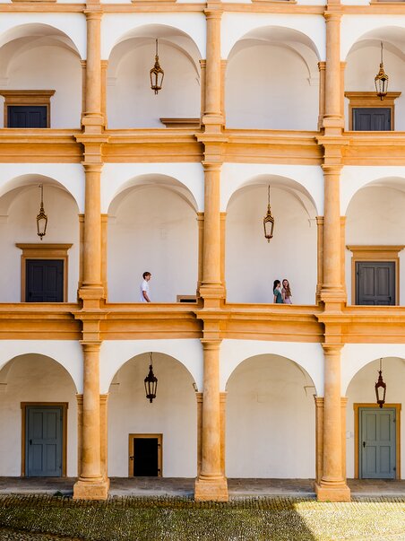 Inner courtyard of Eggenberg Palace with arches and people. | © Graz Tourismus - Mias Photoart