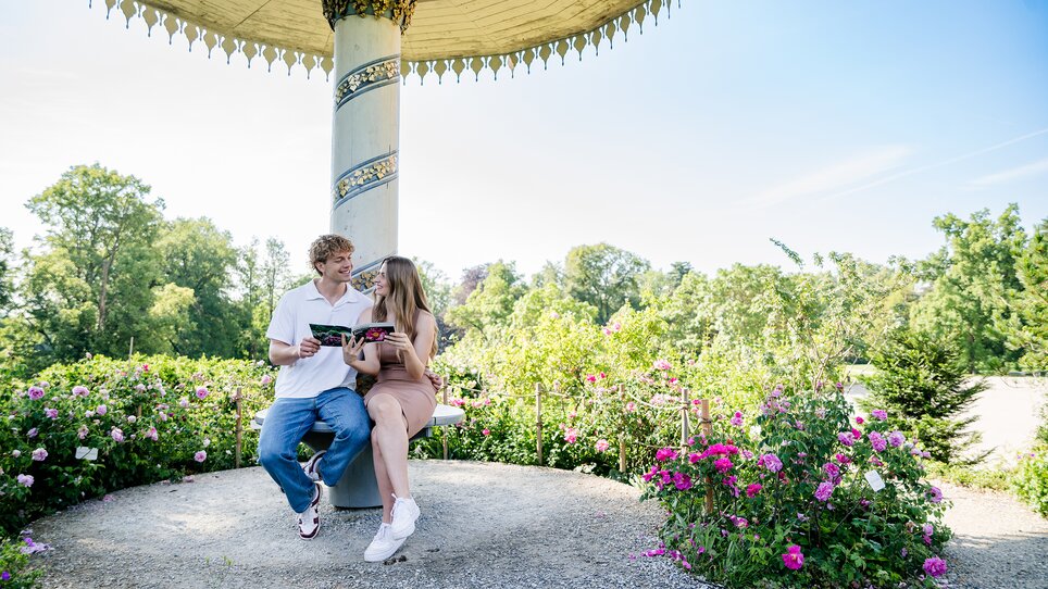 Couple sitting in the park around Eggenberg Palace reading a book. | © Graz Tourismus - Mias Photoart