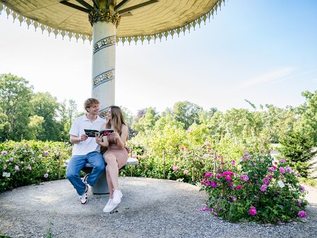 Couple sitting in the park around Eggenberg Palace reading a book. | © Graz Tourismus - Mias Photoart