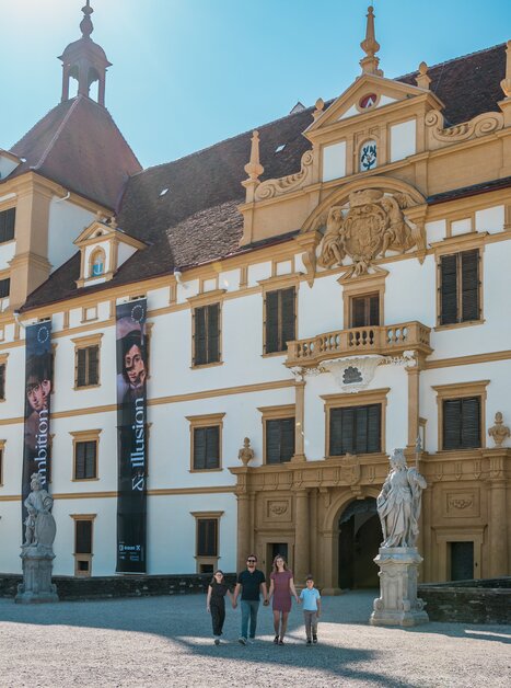 Besucher vor einem kunstvollen Schloss mit großen Bannern. | © Graz Tourismus - Mias Photoart