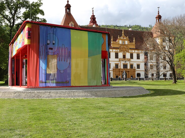 Ein modernes Gebäude mit buntem Vorhang und Kunstwerken, daneben ein historisches Schloss. | © Universalmuseum Joanneum - J. Kucek - Bildrecht Wien 2025