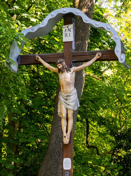Wooden cross with Christ statue, surrounded by trees. | © Graz Tourismus - Harry Schiffer