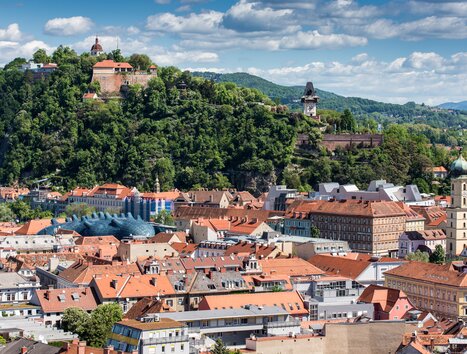 Veduta su Graz con lo Schlossberg, la Torre dell’Orologio e il Kunsthaus. | © Graz Tourismus - Harry Schiffer