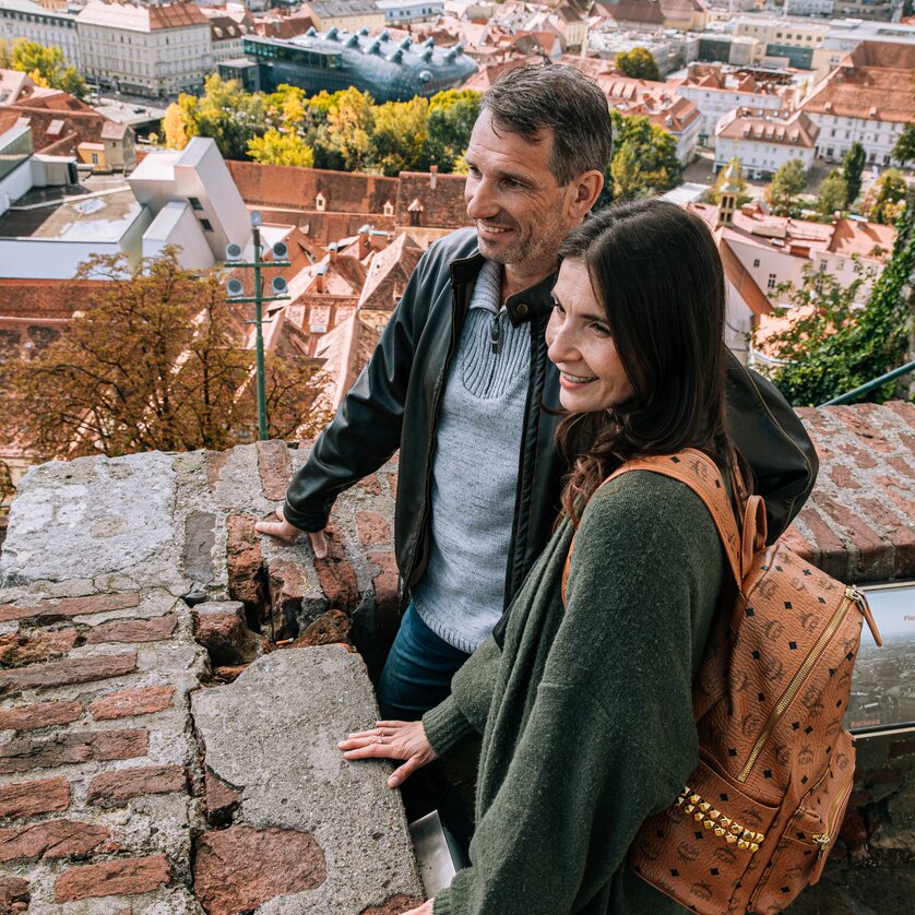 Ein Paar genießt die Aussicht auf Graz vom Schlossberg. | © Graz Tourismus