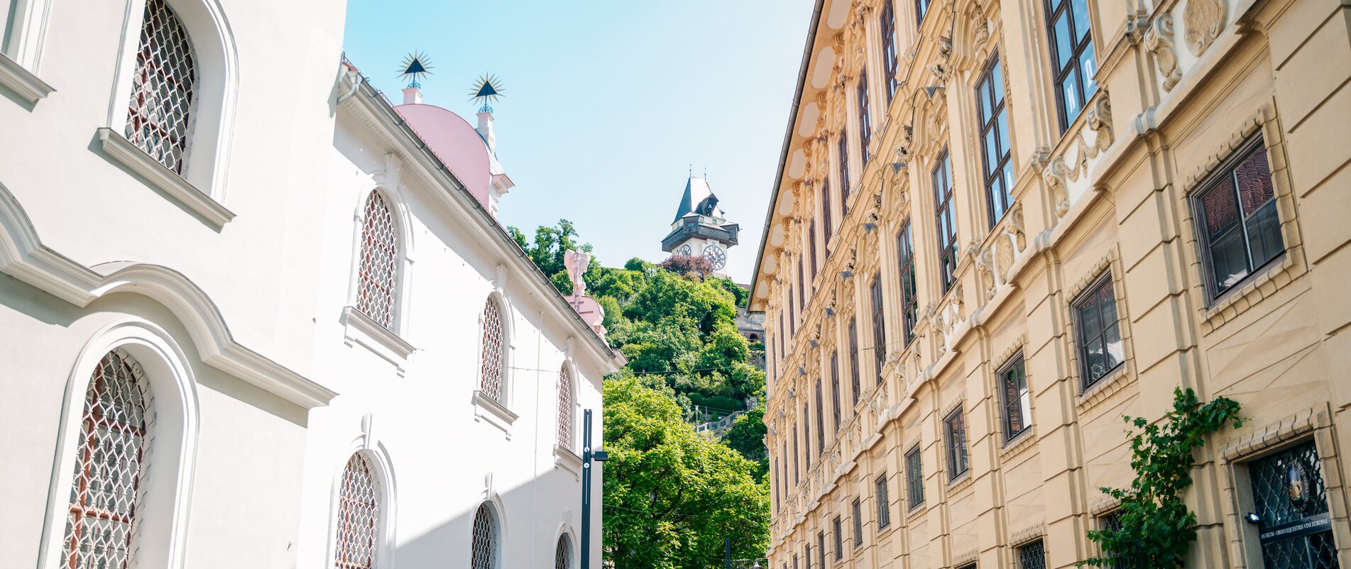 Zwei Frauen spazieren am Schlossbergplatz in Graz, Uhrturm im Hintergrund. | © Graz Tourismus - Mias Photoart