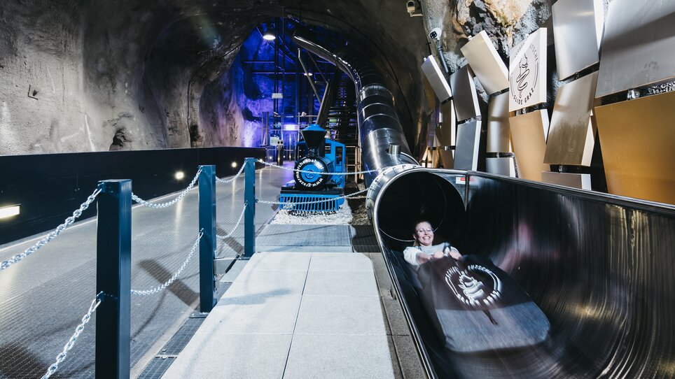 Ein Besucher auf der Schlossbergrutsche in Graz, in einem Tunnel mit Lichteffekten. | © Diesel GmbH