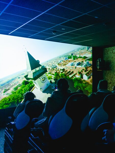 Besucher im 4D Kino im Grazer Schlossberg mit Grazer Uhrturm auf der Kino-Leinwand. | © Region Graz - Mias Photoart