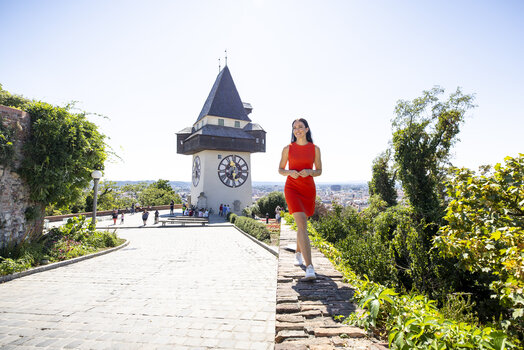 Frau im roten Kleid vor dem Uhrturm in Graz. | © Graz Tourismus - Tom Lamm