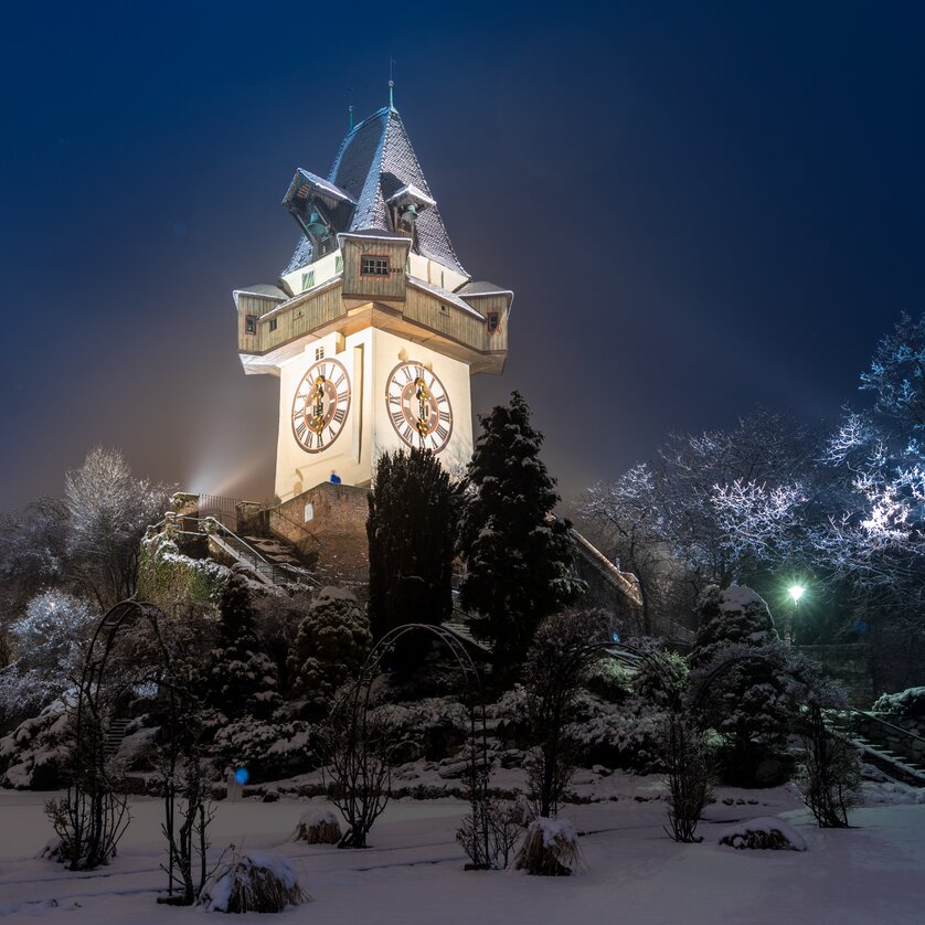 Beleuchteter Uhrturm auf dem Grazer Schlossberg im Schnee. | © Graz Tourismus - Harry Schiffer