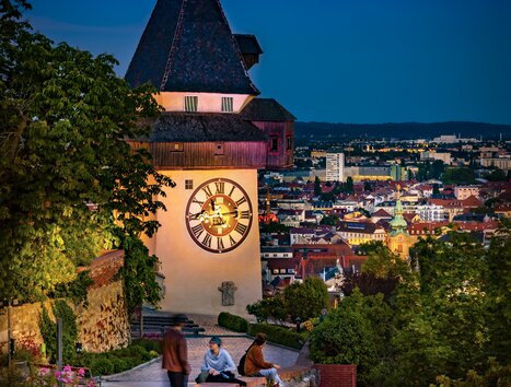 Beleuchteter Uhrturm über Graz bei Dämmerung. | © Graz Tourismus - Werner Krug
