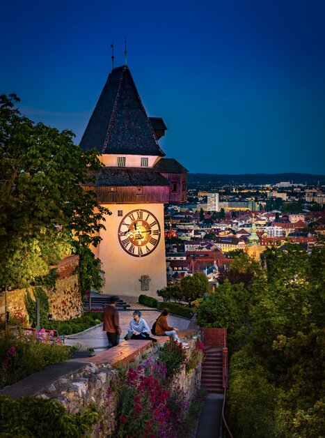Beleuchteter Uhrturm über Graz bei Dämmerung. | © Graz Tourismus - Werner Krug