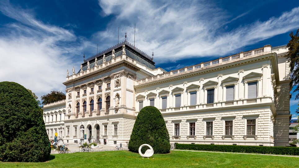 Vista dell'Università Karl Franzens di Graz con un prato verde e un cielo azzurro. | © Graz Tourismus - Harry Schiffer