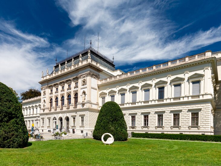 Blick auf die Karl Franzens Universität Graz mit grünem Rasen und blauem Himmel. | © Graz Tourismus - Harry Schiffer