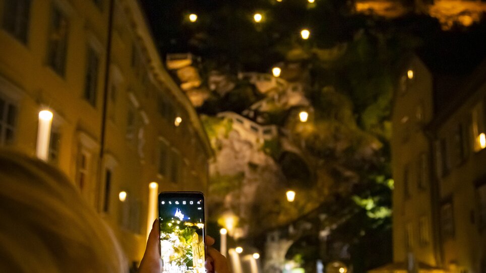 Eine Person fotografiert den beleuchteten Uhrturm in Graz bei Nacht. | © Graz Tourismus - Werner Krug