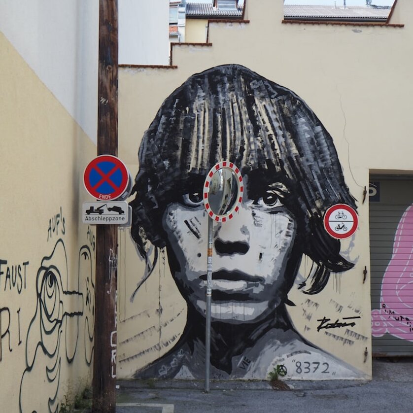 A large mural of a face in Graz, surrounded by traffic signs. | © Elena Paschinger, Creativelena