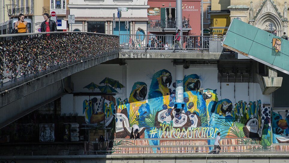 Lebendig bemalte Wand und Menschen an der Mur in Graz. | © Adeline Gressin