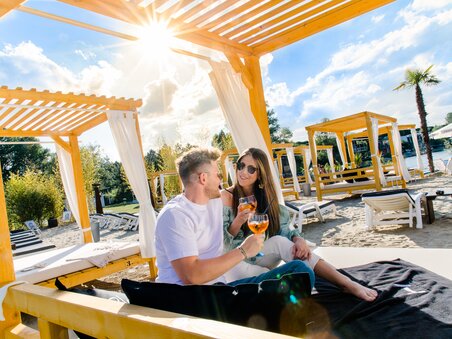 A couple enjoys cocktails in a beach lounge under the sunshine. | © Region Graz - Mias Photoart