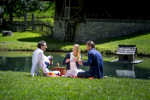 Drei Personen genießen ein Picknick am Wasser in der Natur. | © Region Graz - Tom Lamm