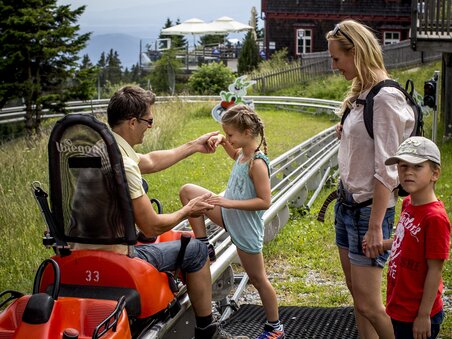 Una famiglia si prepara per una corsa con il bob estivo. | © Region Graz - Tom Lamm