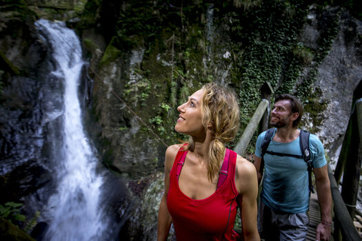 Ein Paar bewundert den Kesselfallklamm Wasserfall während einer Wanderung. | © Region Graz - Tom Lamm