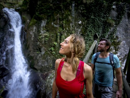 A couple admires the Kesselfallklamm waterfall while hiking. | © Region Graz - Tom Lamm