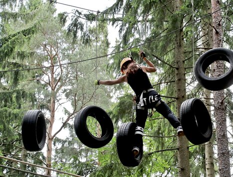 Ein Mädchen balanciert auf Reifen in einem Baumparcours. | © Kletterpark Schöckl - Oberlaender