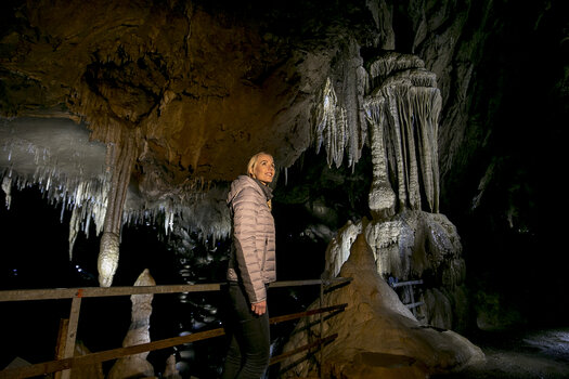 Frau steht in der Lurgrotte Semriach und bewundert beeindruckende Stalaktiten. | © Region Graz - Tom Lamm