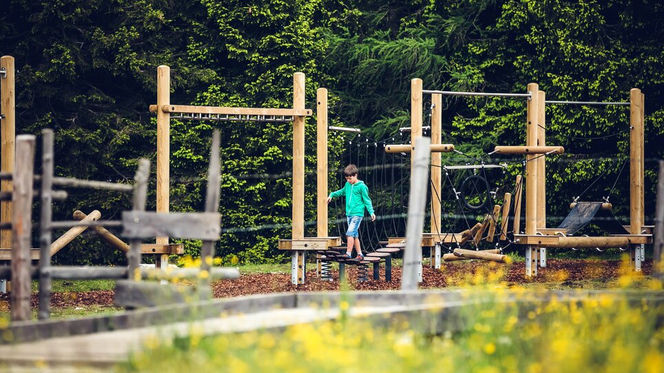 Ein Junge spielt auf einem Klettergerüst in einem Spielplatzumfeld. | © Lupi Spuma