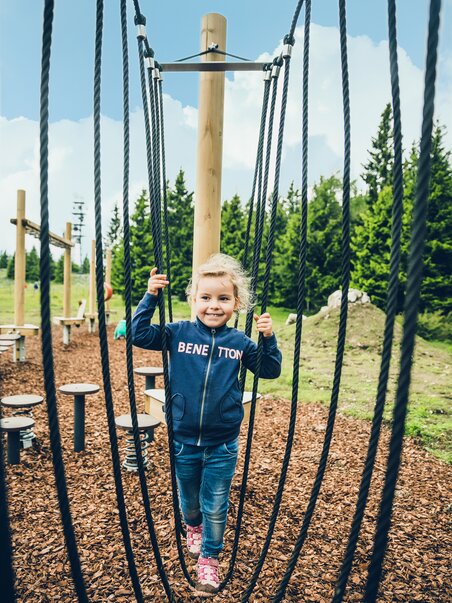 Ein Mädchen spielt fröhlich auf einem Spielplatz mit Seilen. | © Lupi Spuma