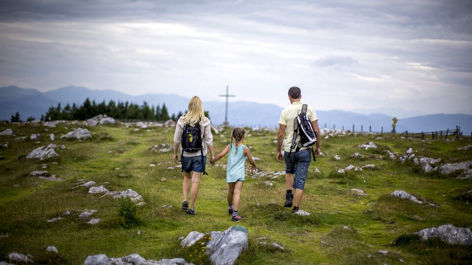 Familie wandert Hand in Hand über eine Wiese am Schöckl. | © Region Graz - Tom Lamm