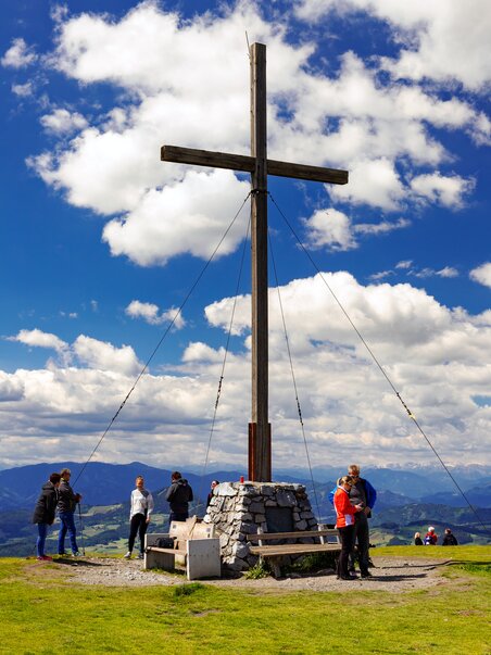 Escursionisti sul Schöckl, con vista sulla croce di montagna e il paesaggio. | © Region Graz - Harry Schiffer
