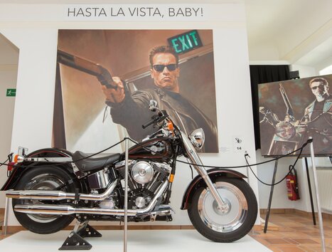 Ein Motorrad vor einem Wandgemälde mit dem Satz "Hasta la Vista, Baby!". | © Region Graz - Harry Schiffer