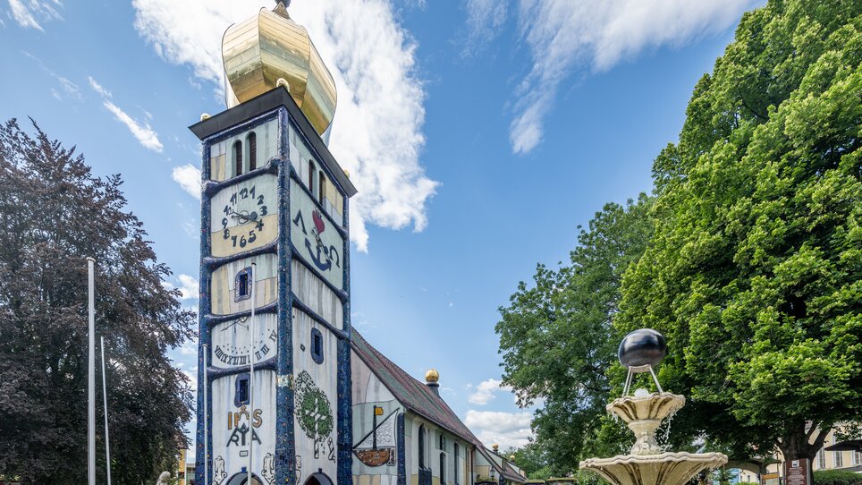 Kirche St. Barbara von Friedensreich Hundertwasser mit einem Brunnen im Vordergrund. | © TV Region Graz - Die Abbilderei