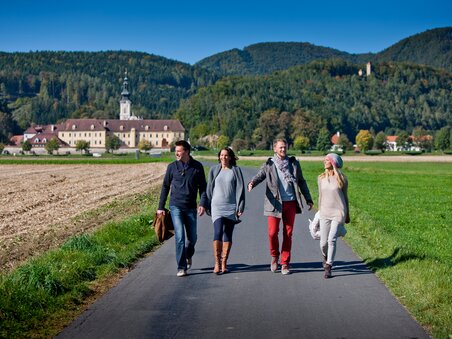 Friends walking along a path near monastery Rein, with mountains in the background. | © Region Graz - Tom Lamm