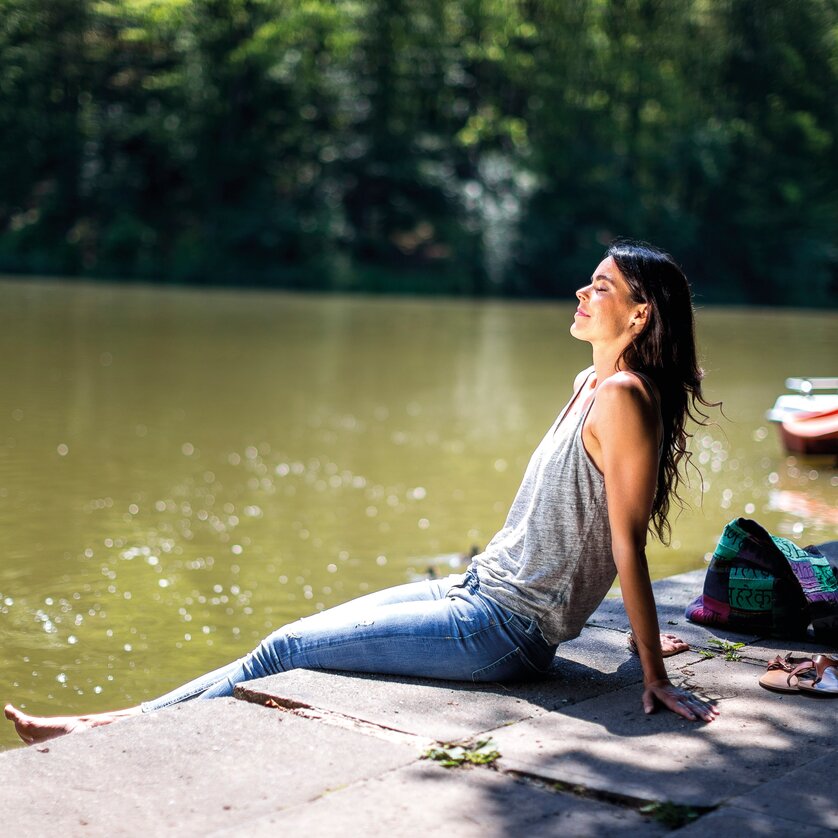 Thalersee | © Region Graz - Tom Lamm A woman sits relaxed by the shore of a lake | © Region Graz - Tom Lamm