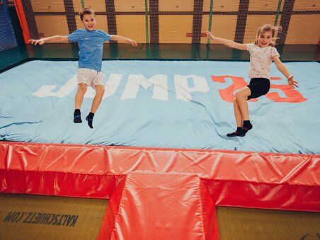 Zwei Kinder springen begeistert auf einem Trampolin mit der Aufschrift JUMP25. | © Lex Karelly