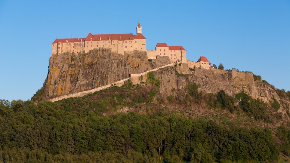 Die Burg Riegersburg, über einem waldigen Hang erbaut. | © Graz Tourismus - Harry Schiffer