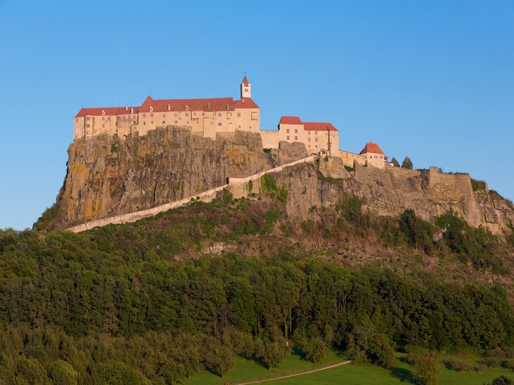 Die Burg Riegersburg, über einem waldigen Hang erbaut. | © Graz Tourismus - Harry Schiffer