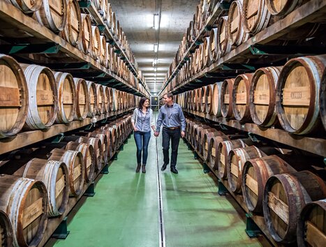 Paar spaziert zwischen Holzfässern in der Essigmanufaktur. | © Gölles