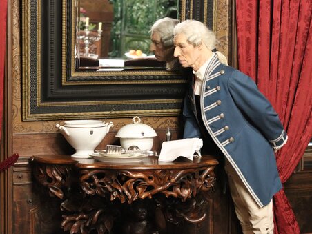 Eine Statue in historischem Gewand steht am Tisch mit Geschirr. | © Bardeau GmbH - Julia Szöne