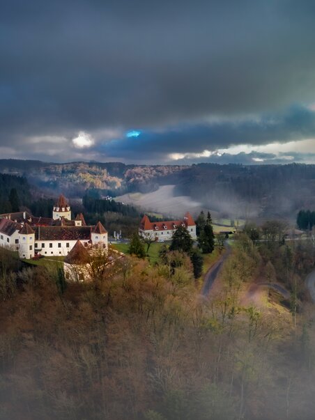 Luftaufnahme von Schloss Kornberg, umgeben von Nebel und Wäldern. | © Schloss Kornberg