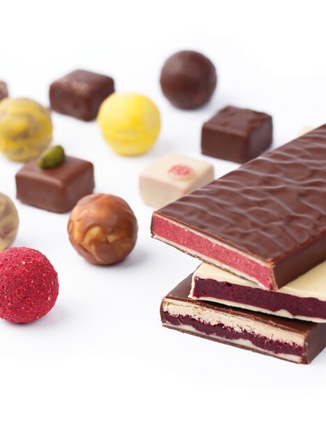 Un assortimento di cioccolatini e praline, tra cui barrette di cioccolato e praline colorate. | © Zotter Schokolade