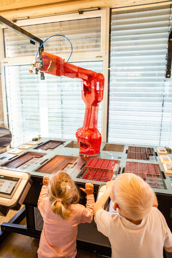 Kinder beobachten einen Roboter an einer Station in der Zotter Erlebniswelt. | © Zotter Schokolade - Jacqueline Jud