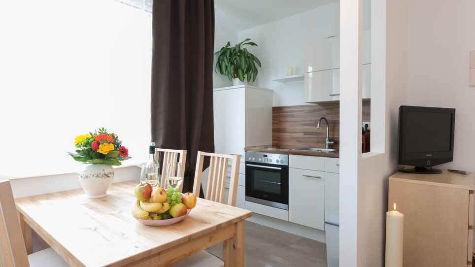 Cozy kitchen featuring a table, chairs, fruit bowl, and plants. | © R. Kaiser