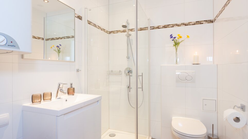 Bright bathroom featuring a shower, sink, and toilet. | © R. Kaiser